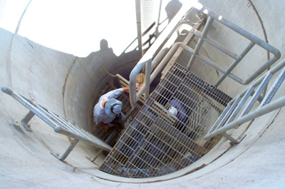 Personnel inspect a seepage monitoring well at a dam during a site examination carried out as part of the Bureau of Reclamation's revised dam safety review process.